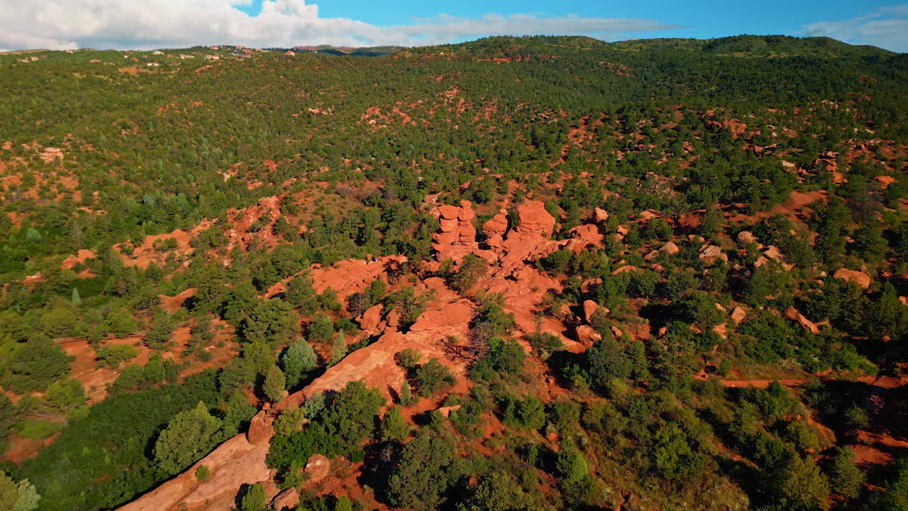 Distancing from a person standing on the unusual red rock gathered in a group. Revealing scenery on the amazing sandstone rock formations in the Garden of the Gods Park, Colorado Springs, Colorado, USA