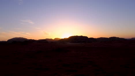 lapso de tiempo de la puesta de sol con los últimos rayos de luz sumergiéndose detrás de montañas escarpadas en el vasto y remoto desierto de wadi rum de jordania, oriente medio