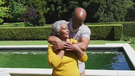 Pareja-Afroamericana-De-Alto-Rango-Enamorada-Sonriendo-Y-Abrazándose-Junto-A-La-Piscina-En-El-Soleado-Jardín