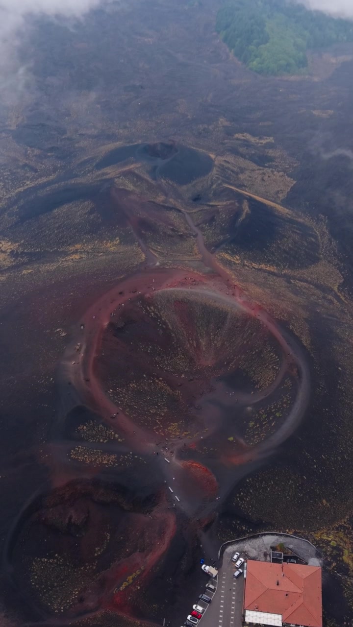 Antico cratere dal bordo rosso sull'Etna appare mentre il drone avanza e si inclina verso il basso.