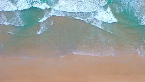 aerial top view blue waves crashing on the beach.