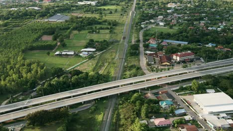 Aerial-wild-view-of-railway-crossing-bridge-and-tree-forest-near-side-with-traffic-on-the-road-in-Khonkaen,-Thailand