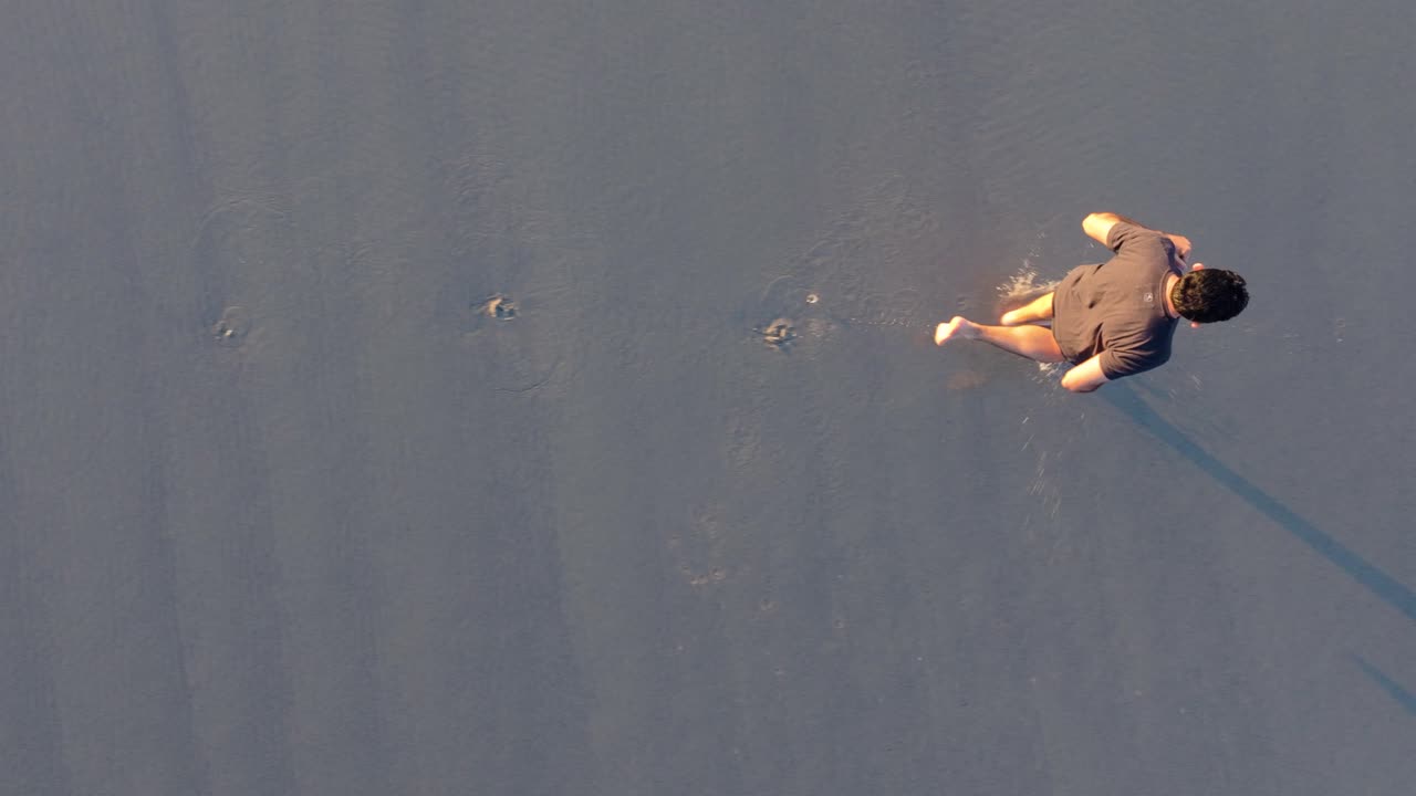 Footprints Of A Man Running On The Seacoast. Aerial Tracking Shot