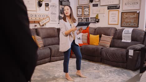 a young furniture sales woman uses a tablet device to help a customer make a purchase inside a store