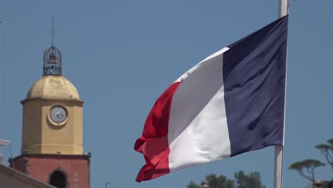 french flag in front of the tower of the church of saint-tropez