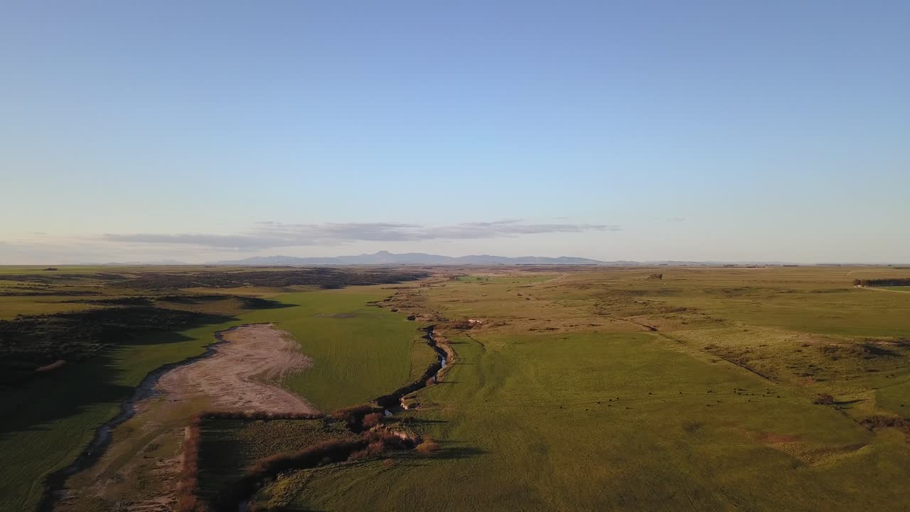 vista aérea del campo rural verde al atardecer con un arroyo que lo atraviesa