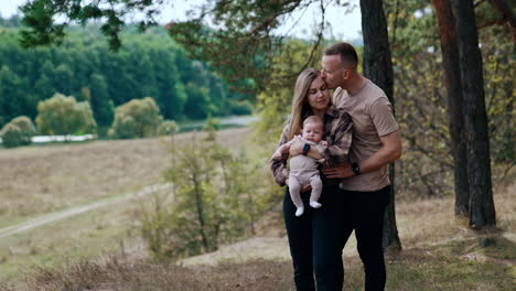 caucasian man embracing his wife holding a newborn. happy family portrait in the nature.