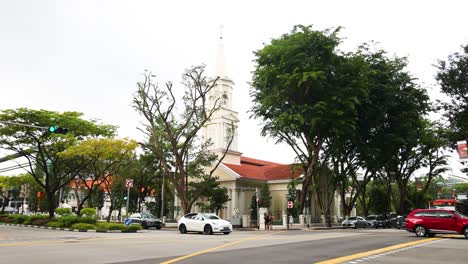 vehículos que se mueven por una calle de la ciudad bordeada de árboles.