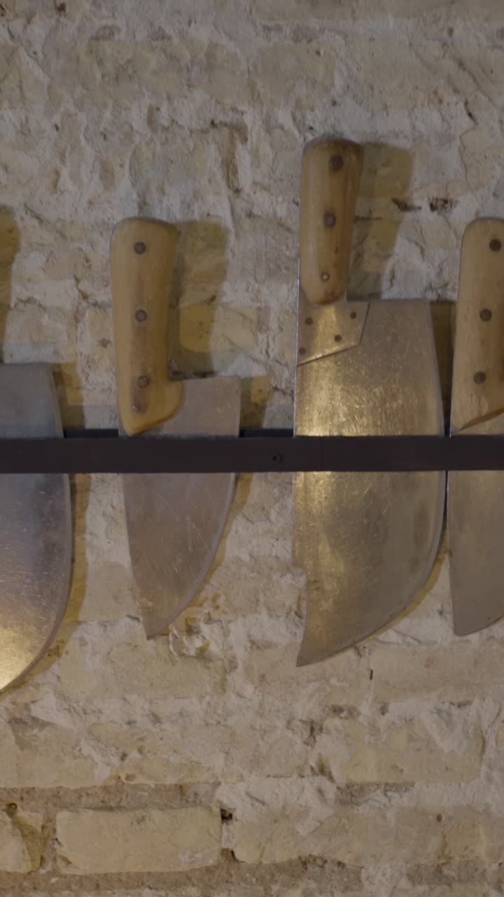 Collection of Large Knives and Cleavers on a Stone Wall