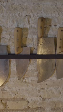 collection of large knives and cleavers on a stone wall