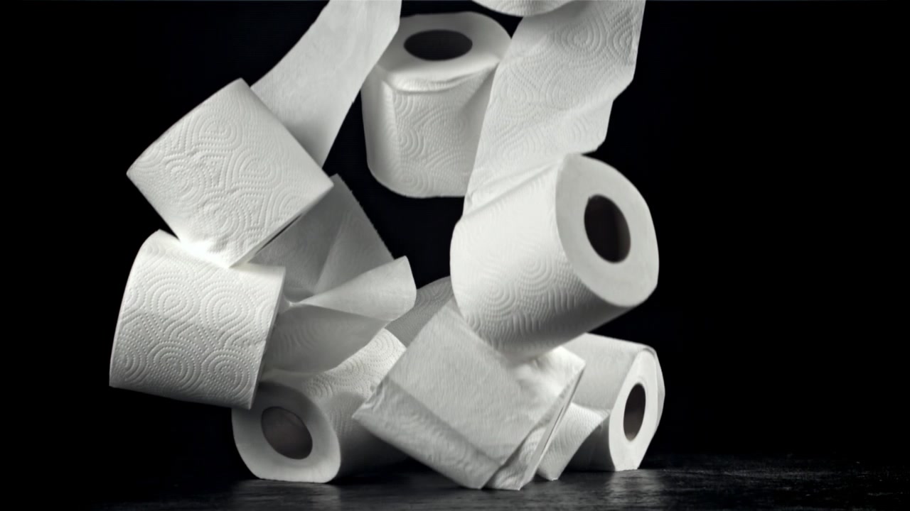 White Toilet Paper Rolls Falling on Black Background