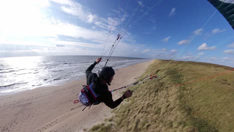 siguiente toma de acción de un parapente extremo deslizando a través de las dunas a lo largo de una playa mostrando increíble habilidad y audacia