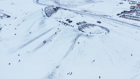 aerial view of people enjoying snowy hill for sledding during winter time