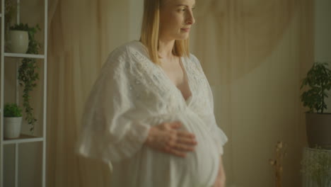 pregnant woman embracing belly with gypsophila bouquet