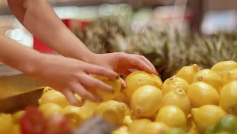 manos de mujer colocando limones en una tienda de comestibles