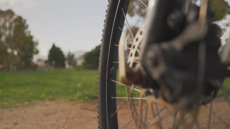 Cerrar-La-Rueda-De-La-Bicicleta,-Con-Un-Paisaje-Borroso-En-El-Fondo-4k