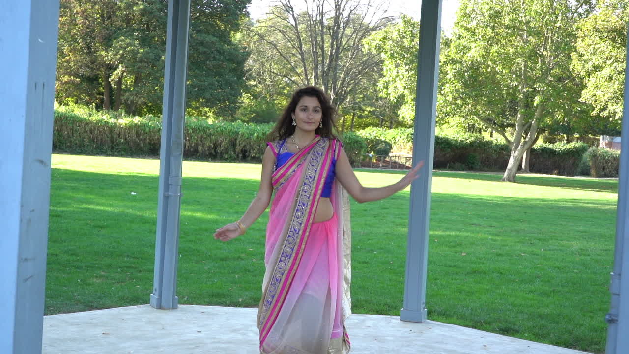 Giovane donna bellissima vestita con abiti tradizionali indiani, che danza all'aperto.