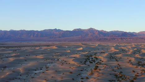 wavy sand dunes with mountains in the background