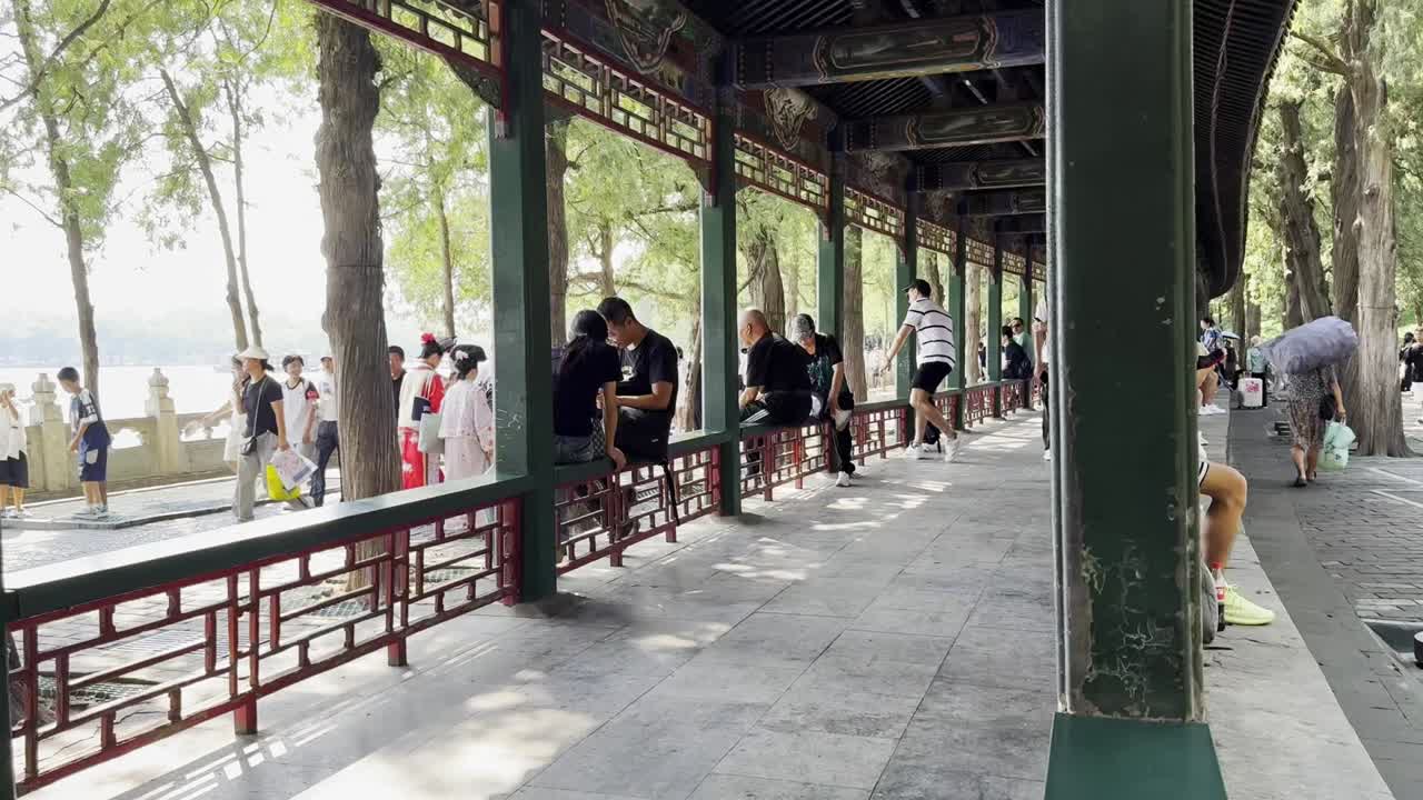 Visitors relax by the columns during a bustling summer afternoon at the Summer Palace in Beijing