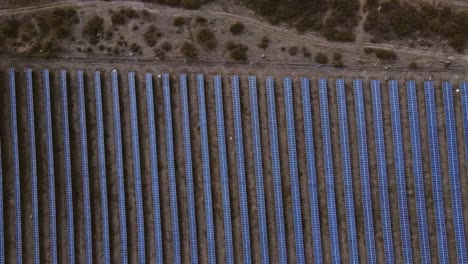 Cámara-Lenta-Aérea-De-Filas-Simétricas-De-Paneles-Solares-En-Zona-Rural,-Vista-Aérea-Superior