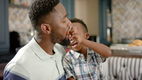 happy african american father and son having breakfast, in slow motion