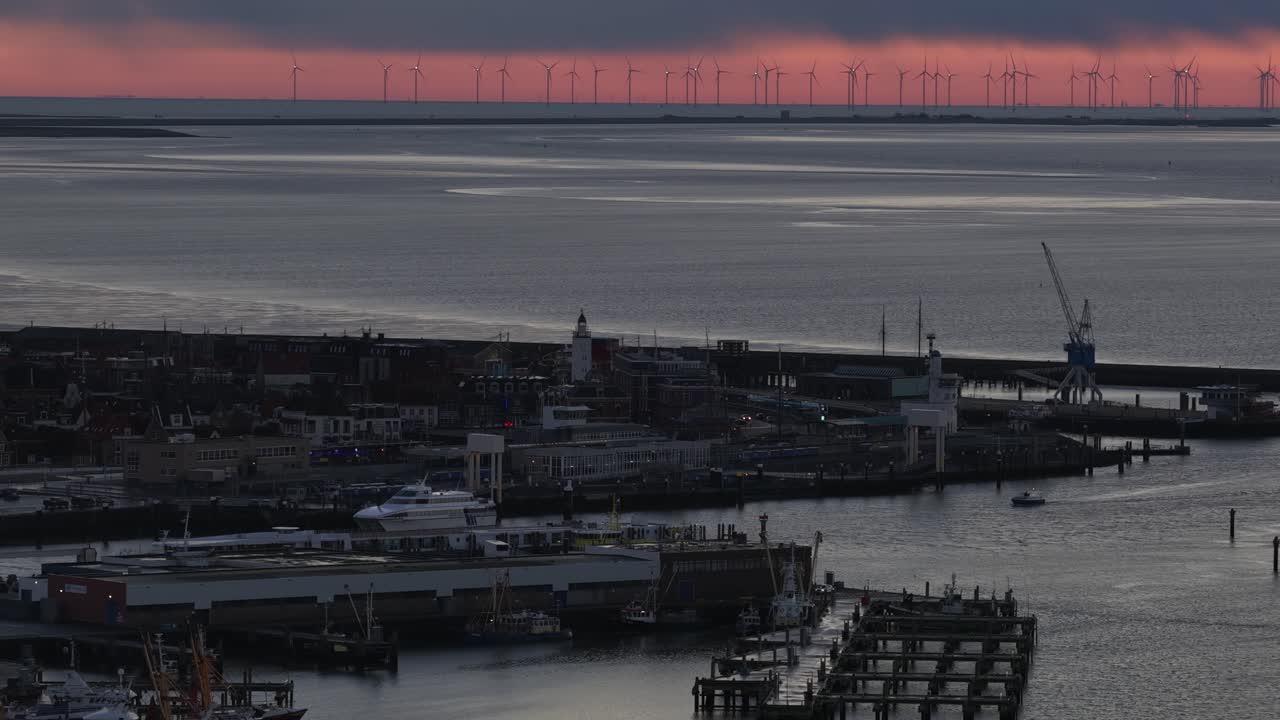 Aerial drone video of the industrial sea port of Harlingen, Friesland, at dusk on the Wadden Sea, showcasing a mix of seagoing vessels, ferries, Brown Fleet historic ships, and official service boats