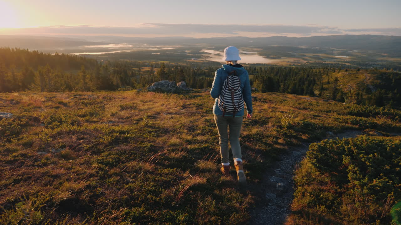 una mujer viajera con una mochila a la espalda camina por las pintorescas tierras altas de noruega j