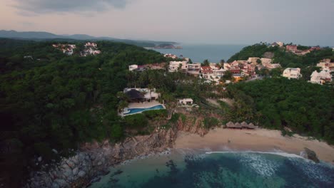 Puesta-De-Sol-Sobre-Huatulco,-México-Con-Casas-Costeras-Y-Densa-Vegetación---Aérea