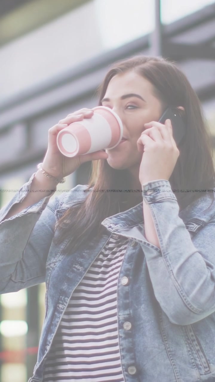 Video verticale: Donna che riceve una chiamata, tenendo il telefono all'orecchio e sorseggiando caffè durante una conversazione di lavoro.
