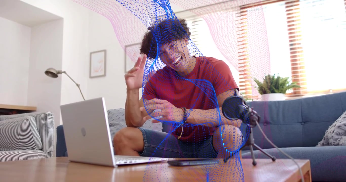 Content creator seduto sul divano che attiva un'onda digitale sul laptop mentre parla e interagisce.