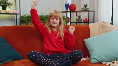 happy toddler child girl dancing and moving to rhythm making trendy dub dance gesture at modern home