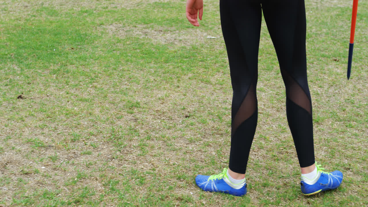 여자 선수가 스포츠 장소에서 창을 던지는 연습을 하는 낮은 섹션 4k
