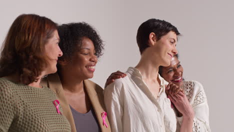 portrait de studio en gros plan d'un groupe multi-racial de femmes souriantes d'âges différents portant des rubans roses de sensibilisation au cancer du sein 1