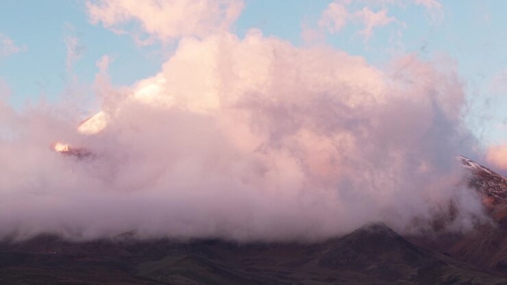 Pink clouds moving in slow motion around the snowy summit of chimborazo volcano in ecuador