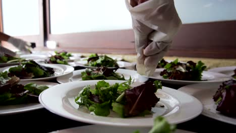 hands putting chopped almonds and blueberries at a salad banquet