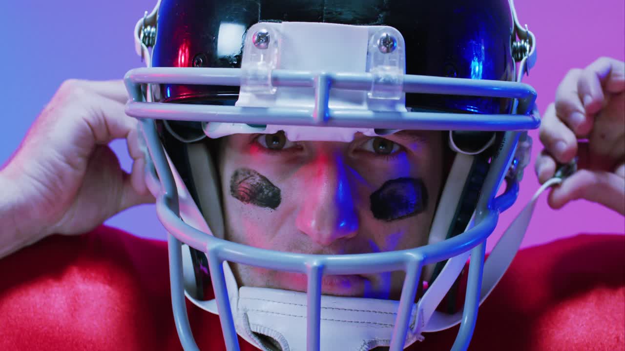 Video ritratto di un giocatore di football americano caucasico con casco su sfondo viola neon