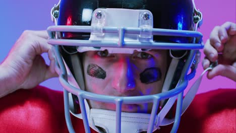 Video-of-portrait-of-caucasian-american-football-player-in-helmet-over-neon-purple-background
