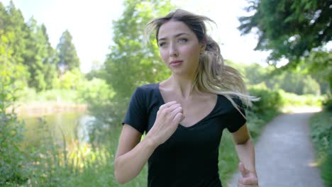 vista del rostro de una mujer cuando comienza a correr en un área boscosa cerca de un estanque