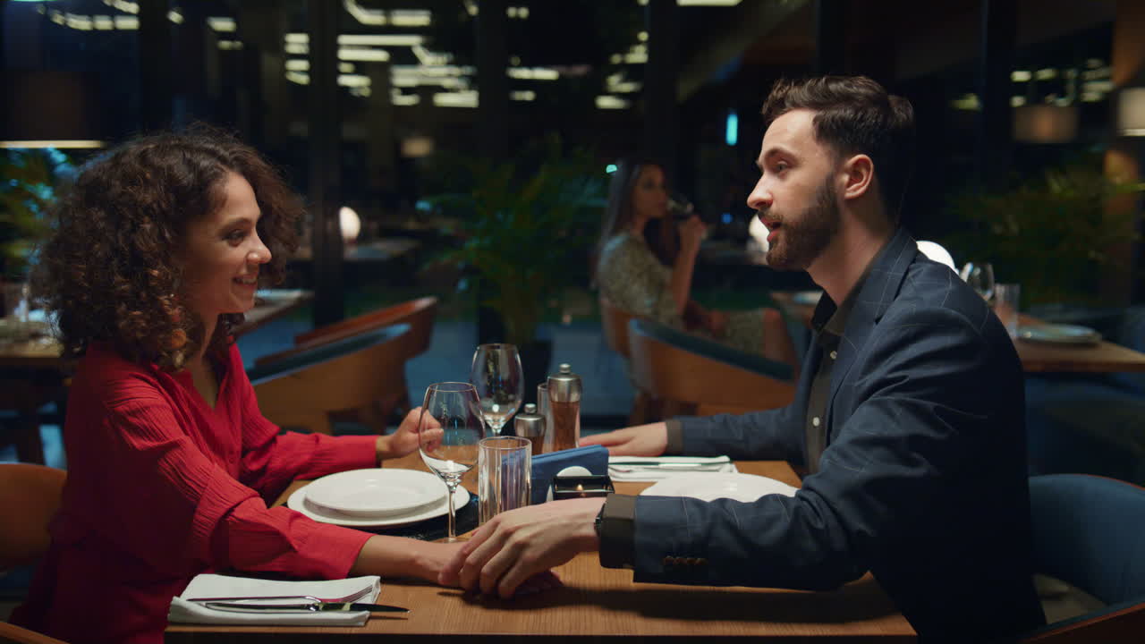 Coppia che flirta e si tiene per mano al ristorante. Uomo che bacia la fidanzata ad un appuntamento a cena.