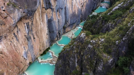 increíble toma de drone del hermoso lago millpu con agua turquesa y montañas vegetadas en un día soleado con hermosos colores