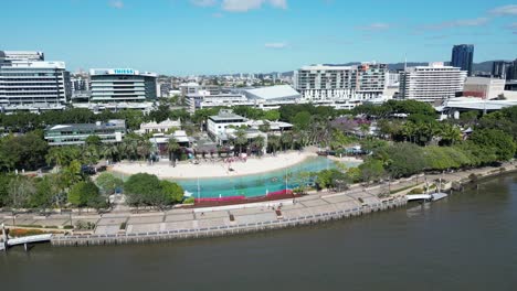 Imágenes-Aéreas-De-South-Bank,-South-Brisbane,-Tomadas-Al-Mediodía,-Con-La-Playa-De-South-Bank,-Zonas-Verdes-Y-El-Río-Brisbane.