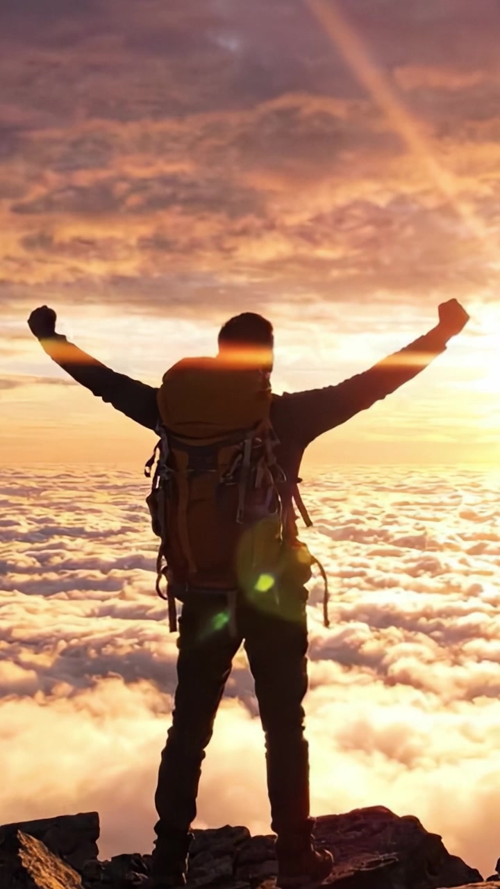 Sopravvissuto trionfante: un escursionista si erge su una cima di montagna sopra le nuvole, ammirando un tramonto mozzafiato dopo una salita impegnativa