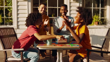 joyful family and friends playing a board game outdoors