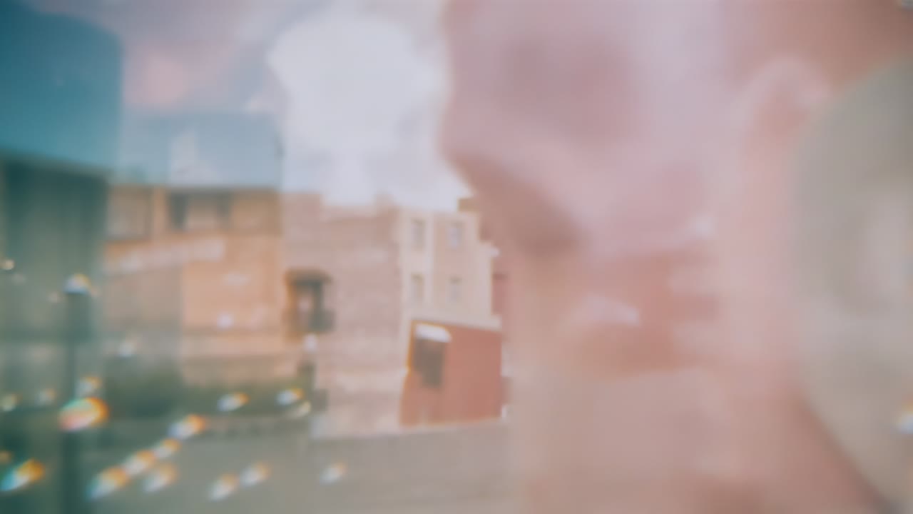 Receding foreground obstruction, camera revealing buildings in courtyard over parapet, lens flare