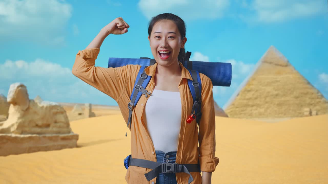 Asian Female Hiker With Mountaineering Backpack Smiling And Flexing Her Bicep While Traveling In Pyramid Of Giza