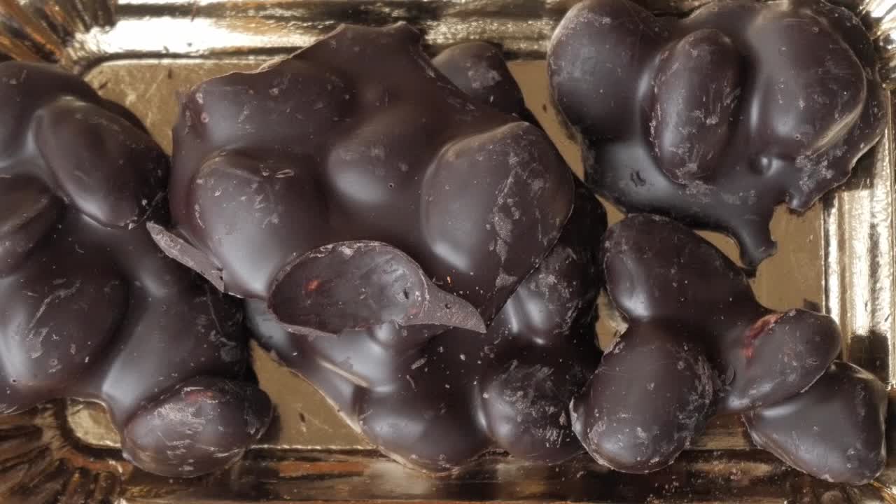 Close-up of chocolate-covered almonds on a shiny tray, delicious indulgence
