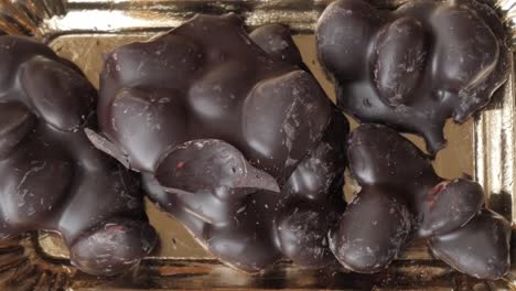 close-up of chocolate-covered almonds on a shiny tray, delicious indulgence