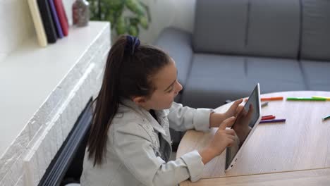 people, children and education concept - girl with tablet pc computer writing at home