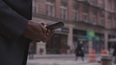 a businessman uses a phone on a city sidewalk