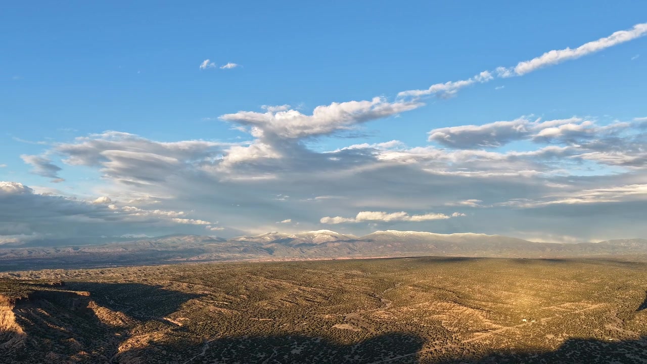 Timelapse 4K con drone cattura un drammatico movimento di nuvole verso una montagna innevata. Il movimento atmosferico cinematografico rivela ombre mutevoli e la luce del tramonto su un aspro paesaggio montano invernale.